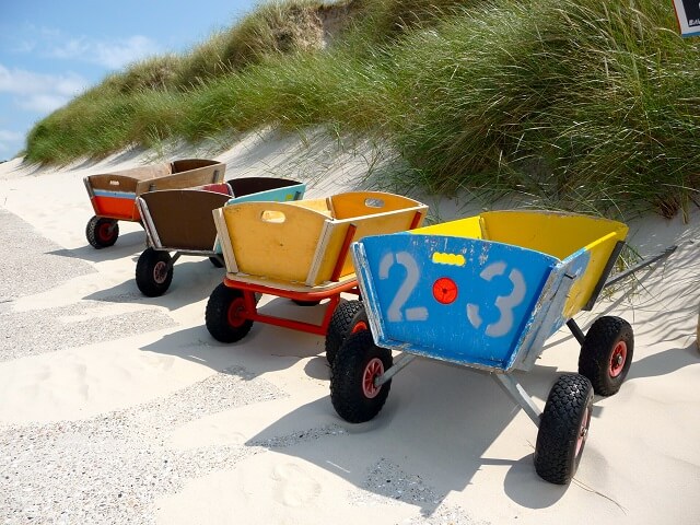 Bunte Bollerwagen stehen auf einem Weg zum Strand